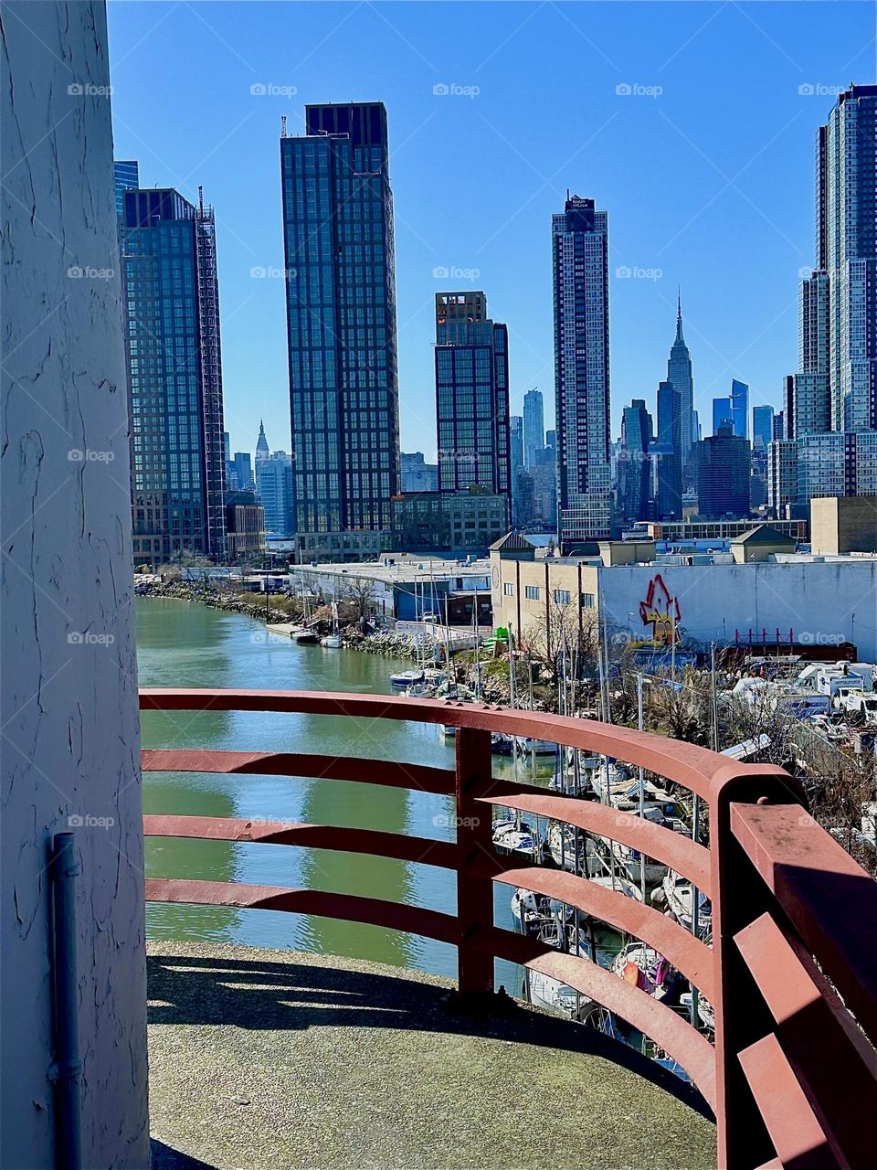 This is „Newtown Creek“ seen from the central outpost of the „Pulaski Bridge“ that connects LIC, Queens to „Greenpoint“, Brooklyn. In the distance we see „Manhattan“ including the „Empire State Building“. 2024. Hypnotic Productions