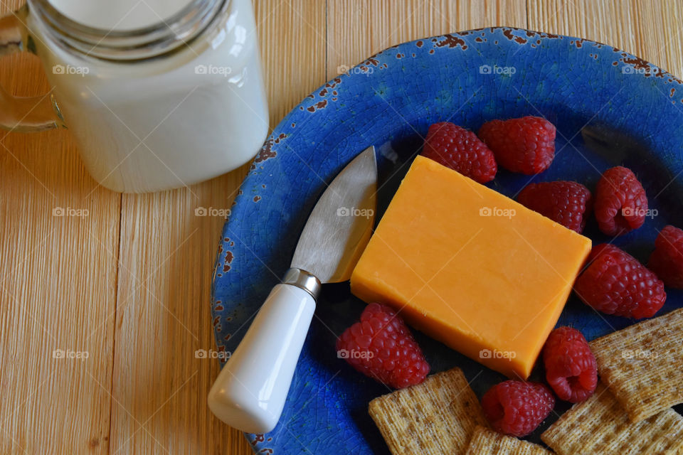 Cold glass of milk with plate of fruit and cheese