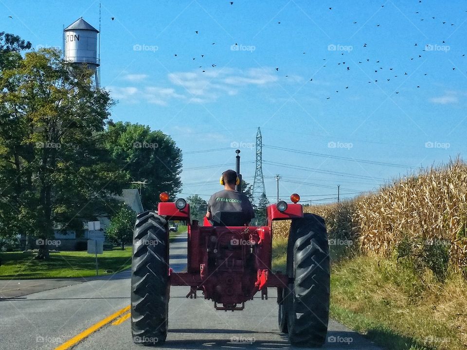 Country living involves tractors and corn fields.