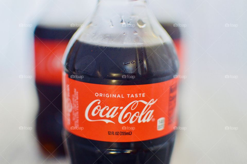 Three plastic bottles of Coca-Cola on a white rustic background