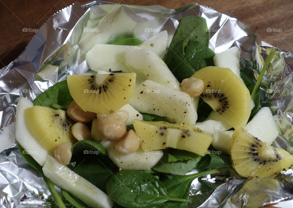 Healthy menu idea: green salad used kiwi, macadamia nuts, apple,spinach, salt, spice and olive oil.
