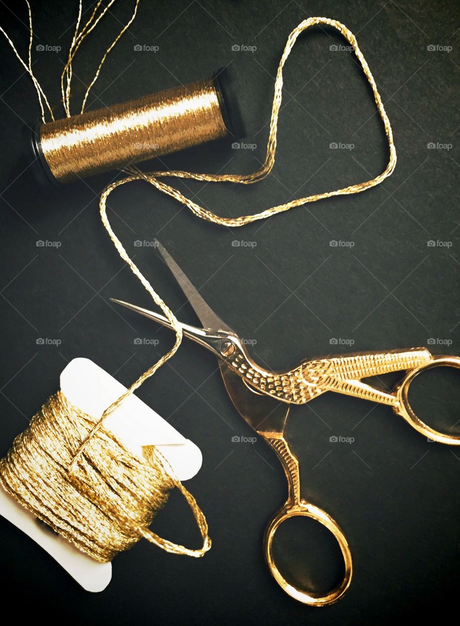 (nominated) Gold - Flat lay of gold embroidery and specialty threads and golden bird needlework scissors on a black background