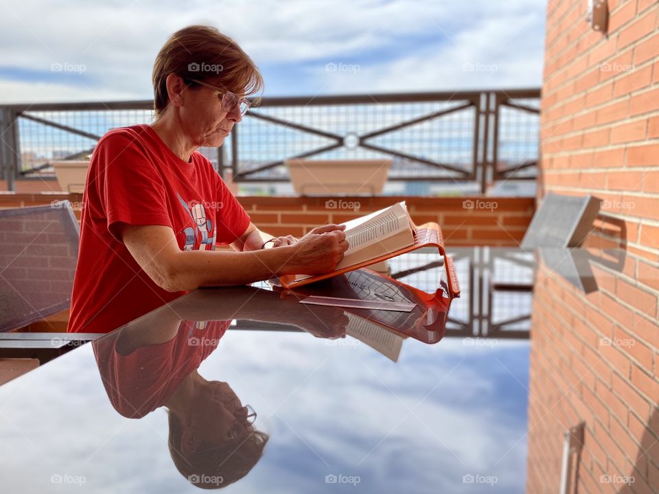 A woman reading a book is reflected on a crystal table