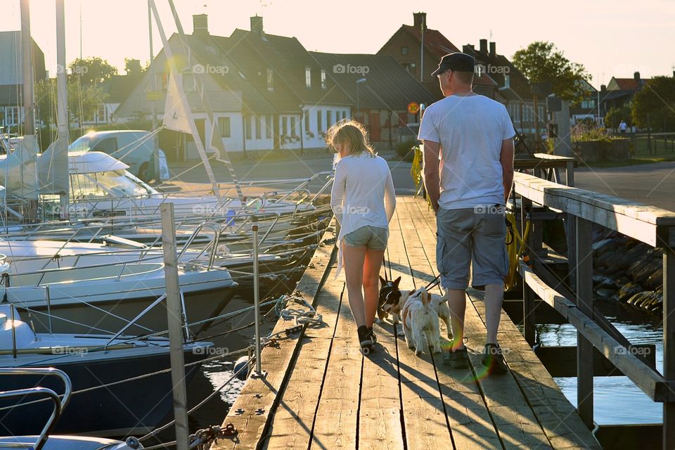 Father and daughter walking on pier with dog