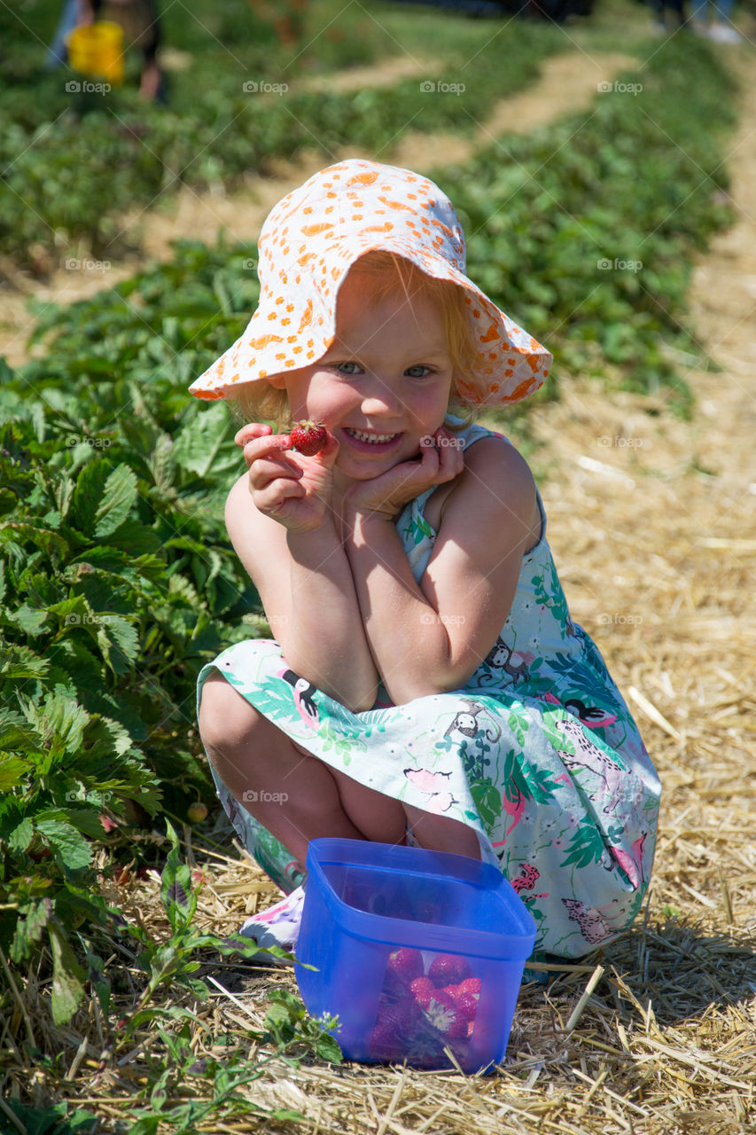 Smiling cute girl holding berries in field