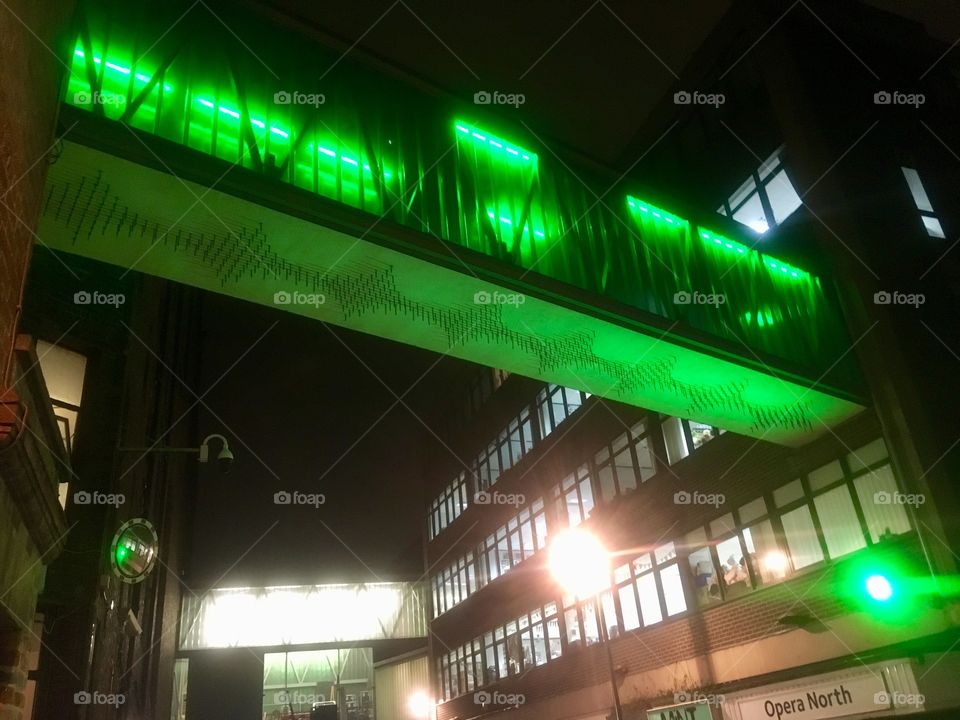 Green lit bridge walkway near the Mint Club, Leeds