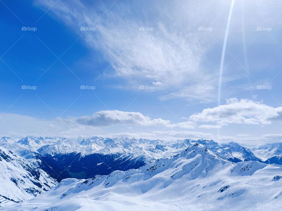 Panorama of snowcapped mountains at snow-fun-park, silvretta-montafon, schruns, austria, in front of a blue cloudy sky