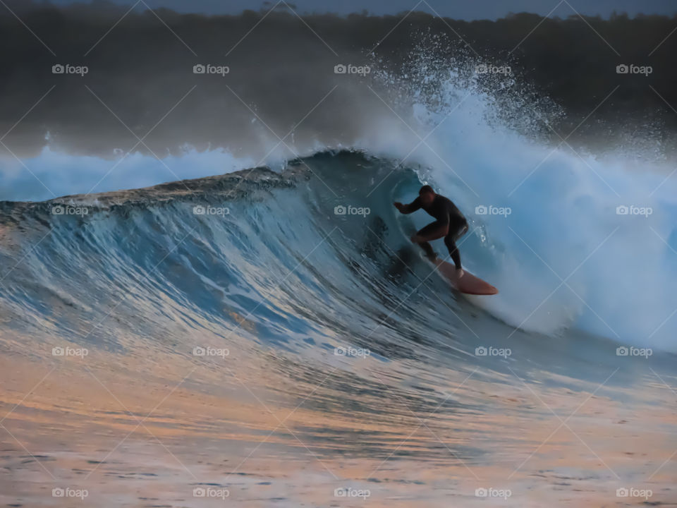 Surfer riding a barrel wave at sunset.