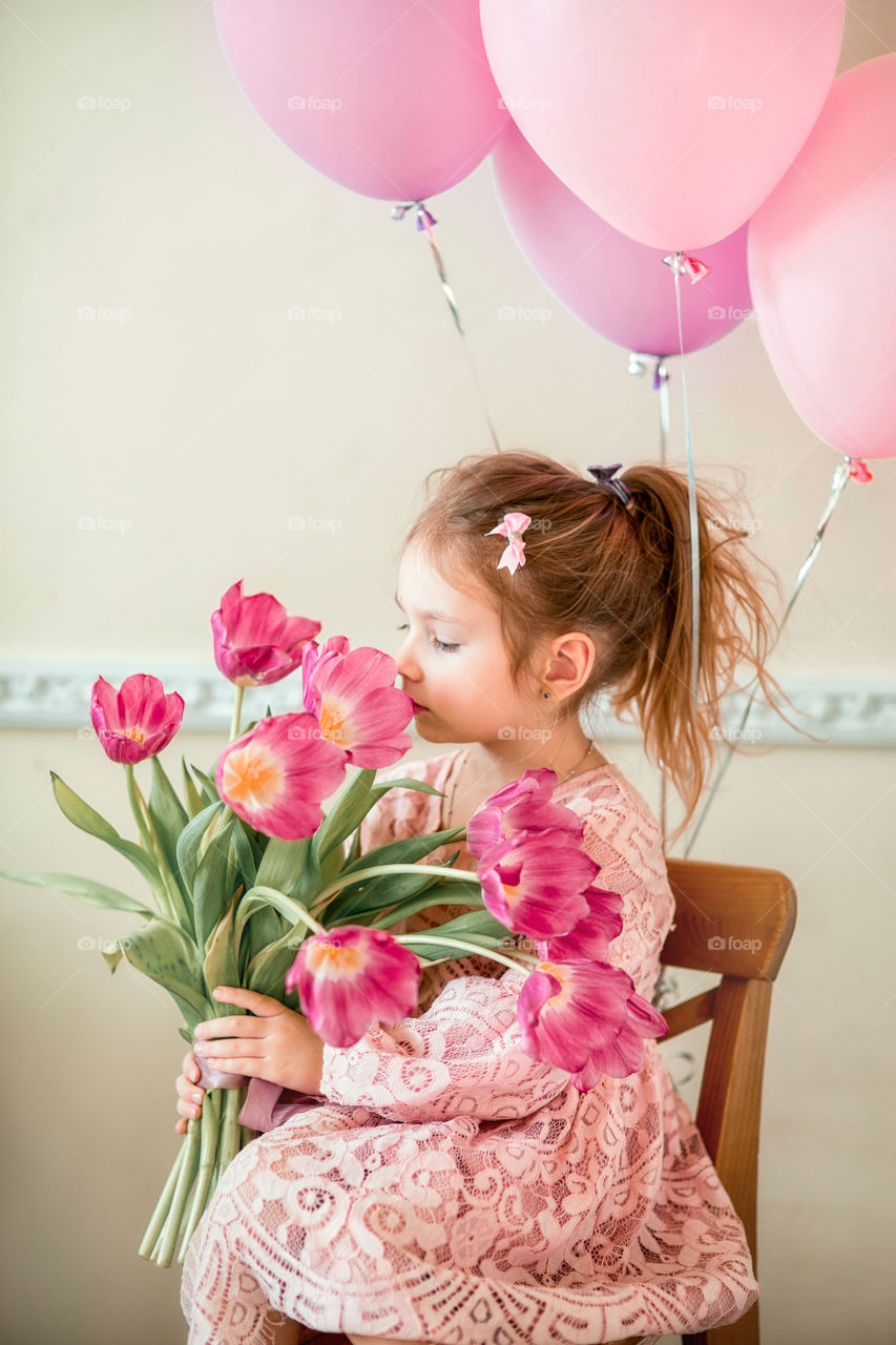 Birthday portrait of a beautiful little girl with tulips bouquet 