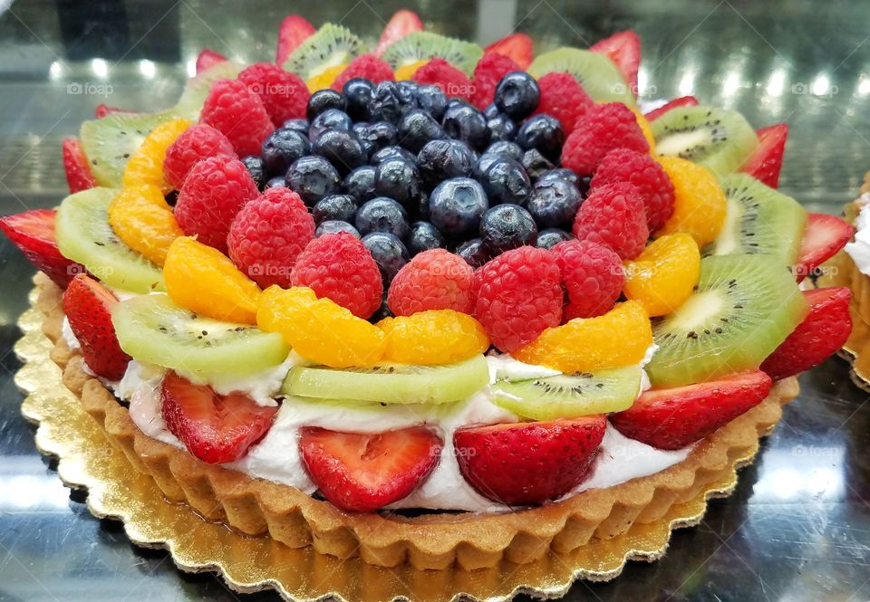 Beautiful and delicious blueberries, kiwis, oranges, raspberries, strawberries and cream pie.