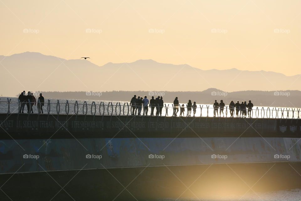 People on the breakwater on sunset