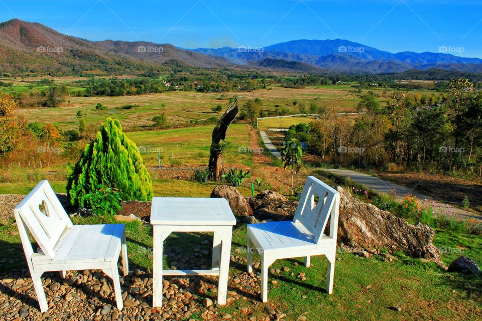 All 3 white chairs and tables were placed at the beautiful natural scenery in the countryside.