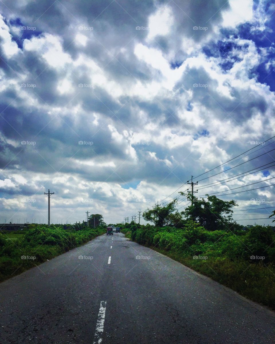 Lonely road under a beautiful white cloudy sky