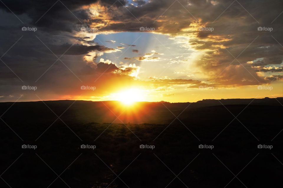 sunset on a canyon with a cloudy sky and the rays that shape the clouds