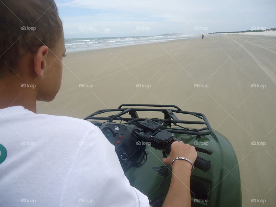 Boy driving a quadricycle on the beach