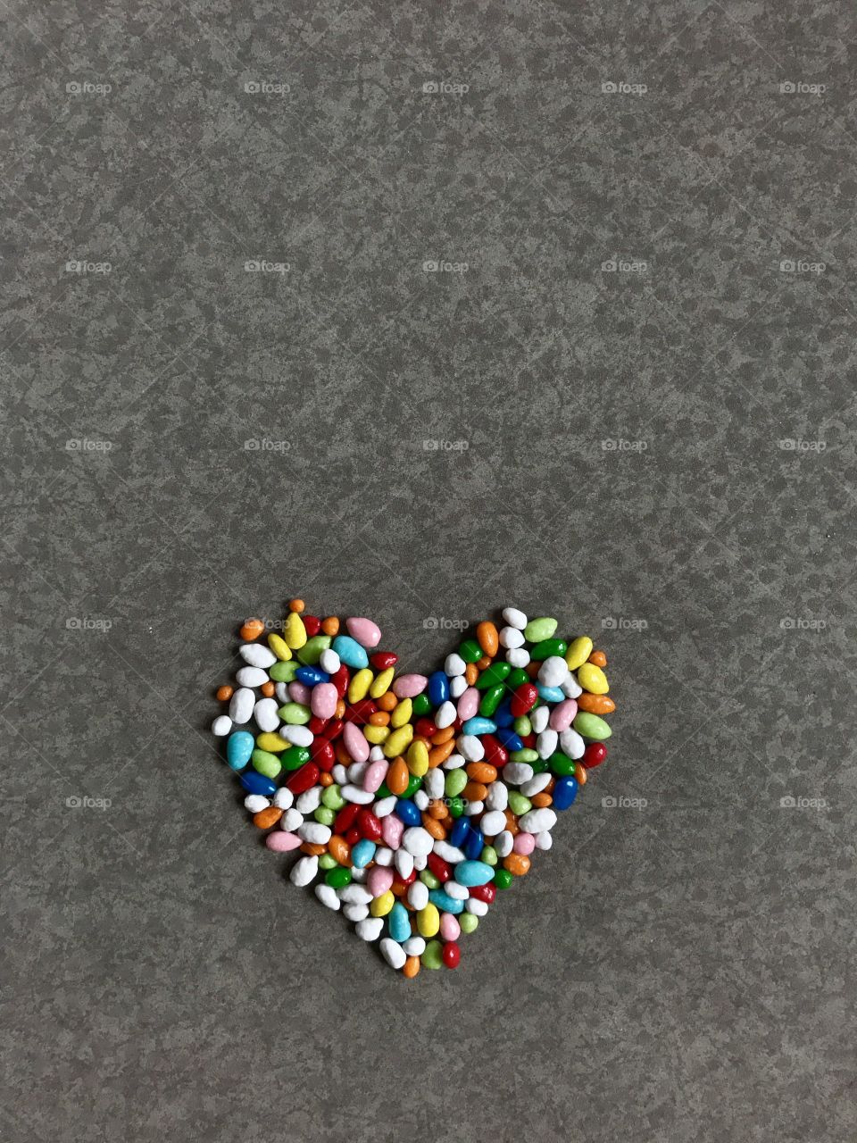 Heart made with multicolor sweets on gray 