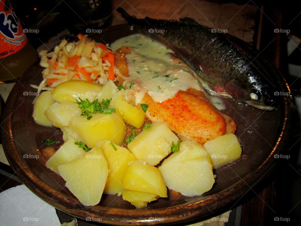 Food on a plate. fried fish trout with potatoes and salad