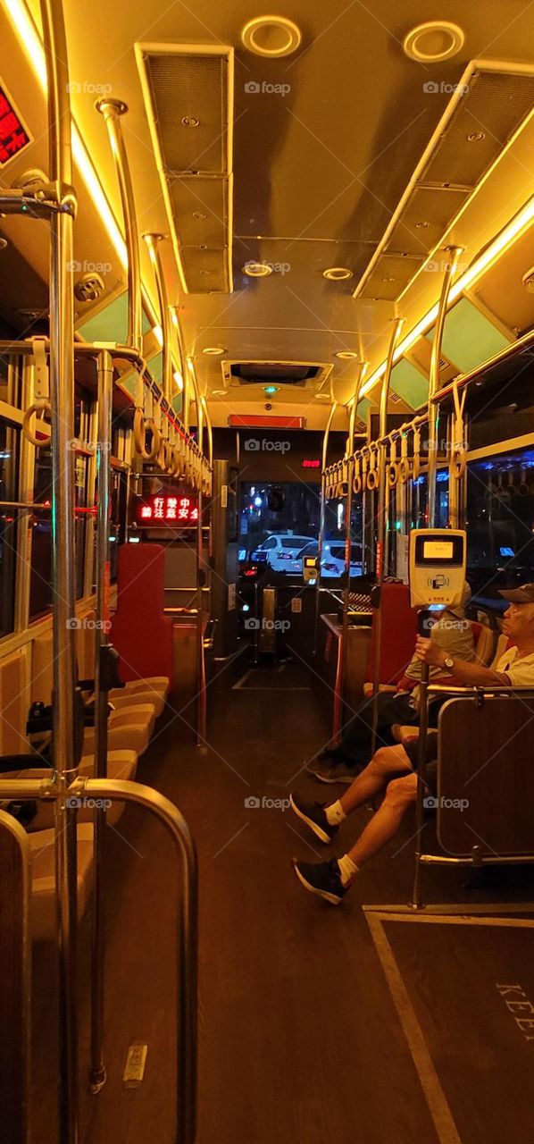 A retro-style bus with a warm yellow light interior. The marquee reads "Please pay attention to safety while driving" in Chinese