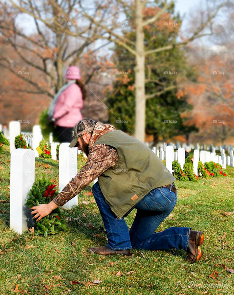 Honoring Veterans. placing a wreath on the grave of a fallen soldier during the wreaths across America