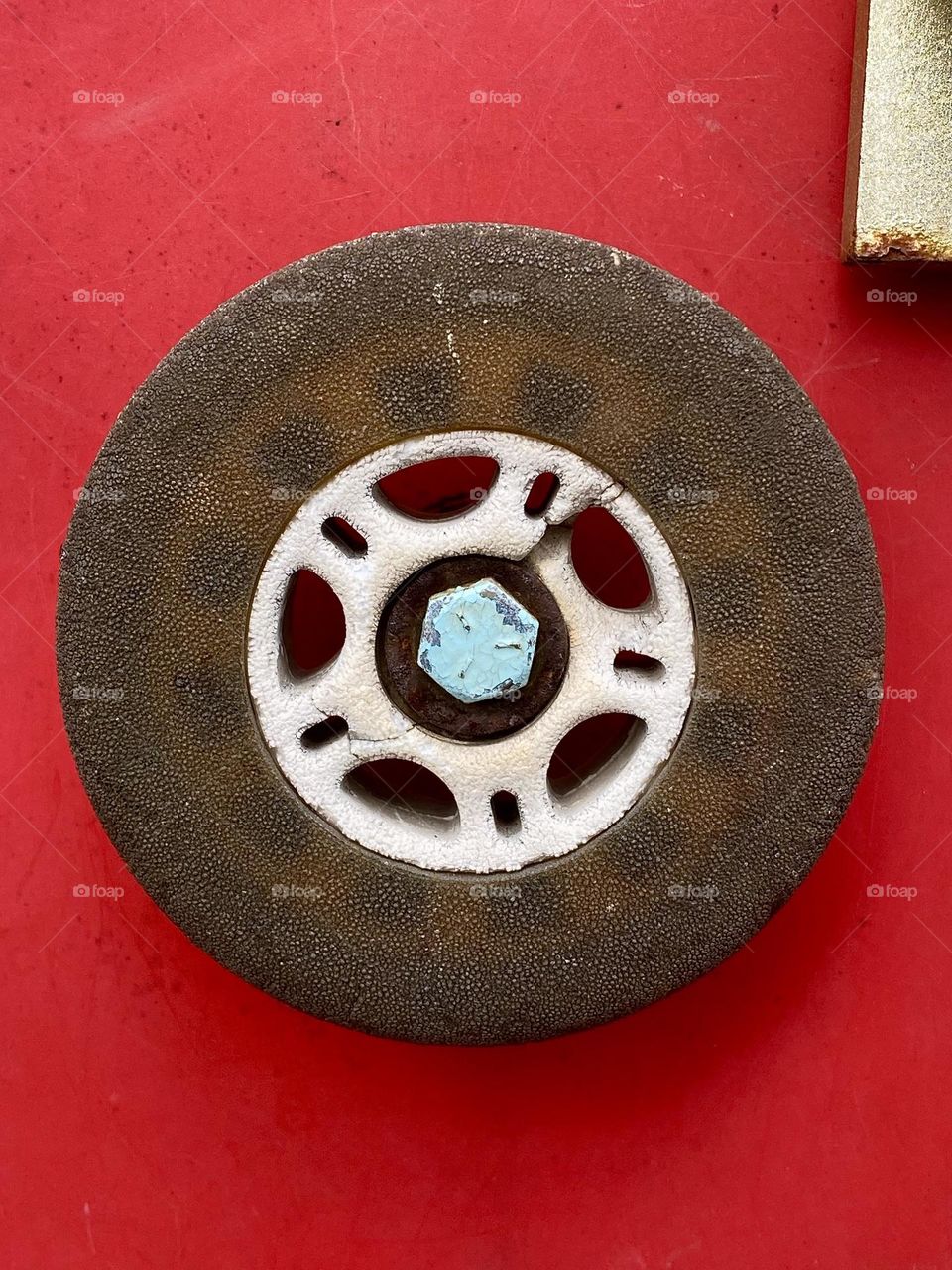Close up of an old cracked rollerblade wheel on a bright red background