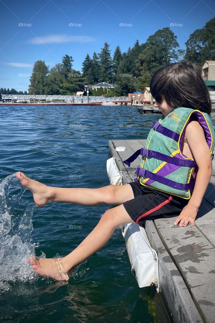 A young child splashes their feet in the cool waters of American Lake, Washington in summertime 