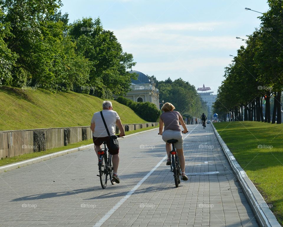 old couple riding on a bikes on a street road summer time