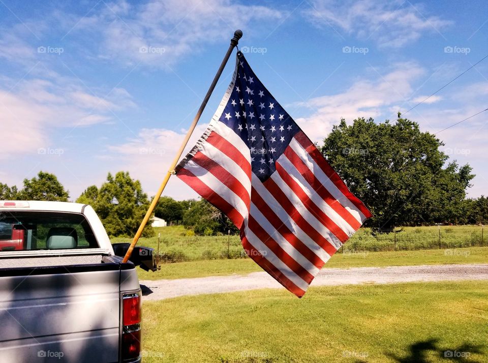 Old Glory the American Flag waving in the Breeze in the back of a pick up teuck on a farm in East Texas