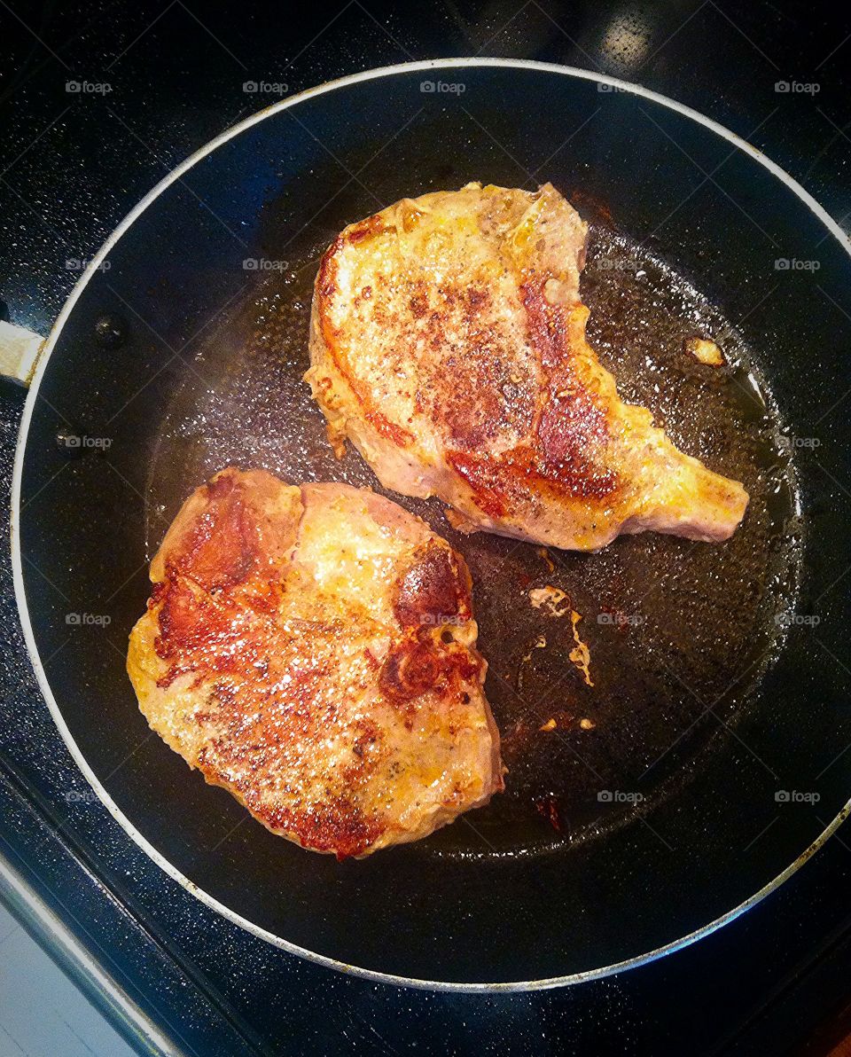 Pork chop sizzling on stovetop. Cooking dinner