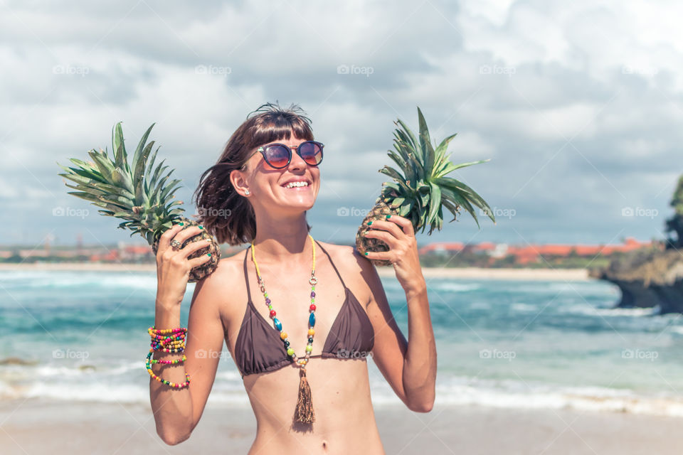 The girl laughs and holds pineapples in her hands.