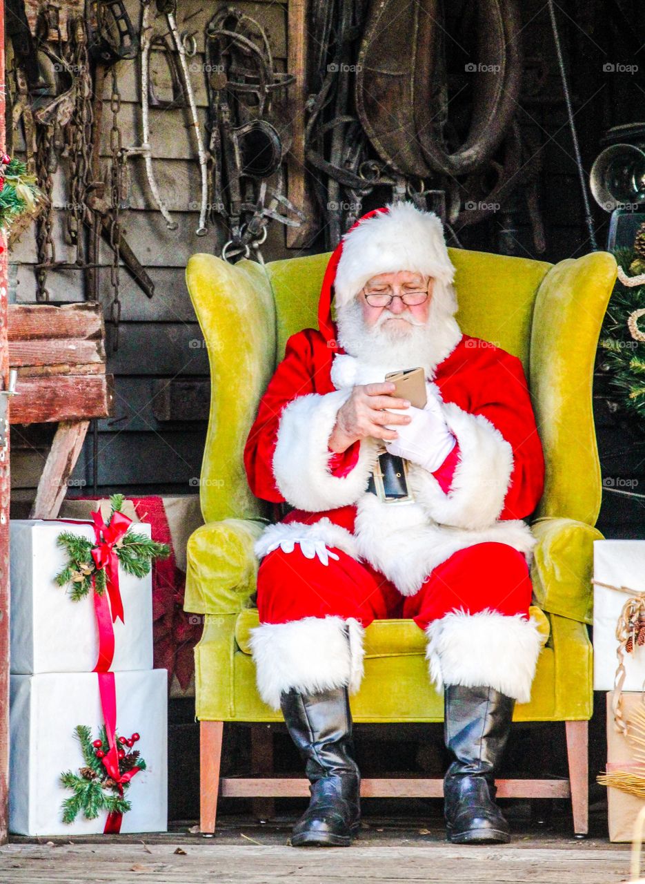 Santa Claus sitting on arm chair using cellphone