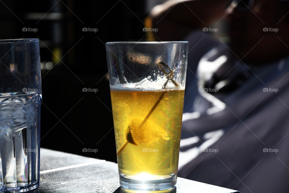 A lime on a stick gets dropped into a glass of beer as a group of friends dine at a restaurant.