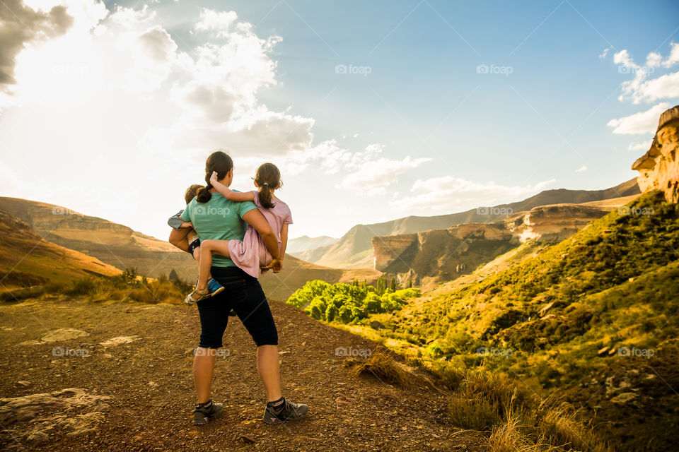 My absolute favorite moment - looking out over Golden Gate in South Africa holding my two children. Image of sunset over sandstone mountains and mom with kids looking at the beautiful scenery.