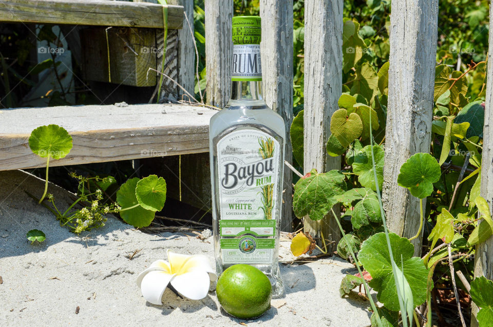 Bottle of white Bayou rum in the sand on a wooden deck