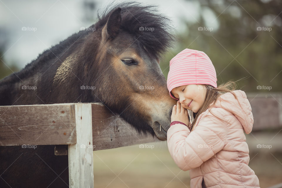 Little girl with pony, outdoor portrait 