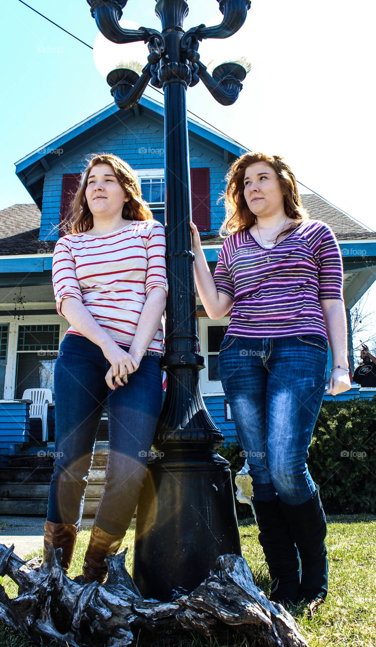 Twin sisters standing near lighting pole