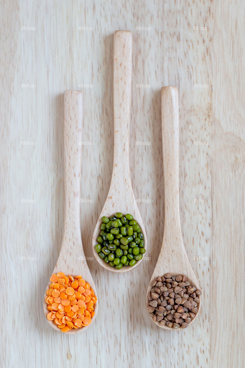 Three spoons with different grains: buckwheat, moong beans and dal