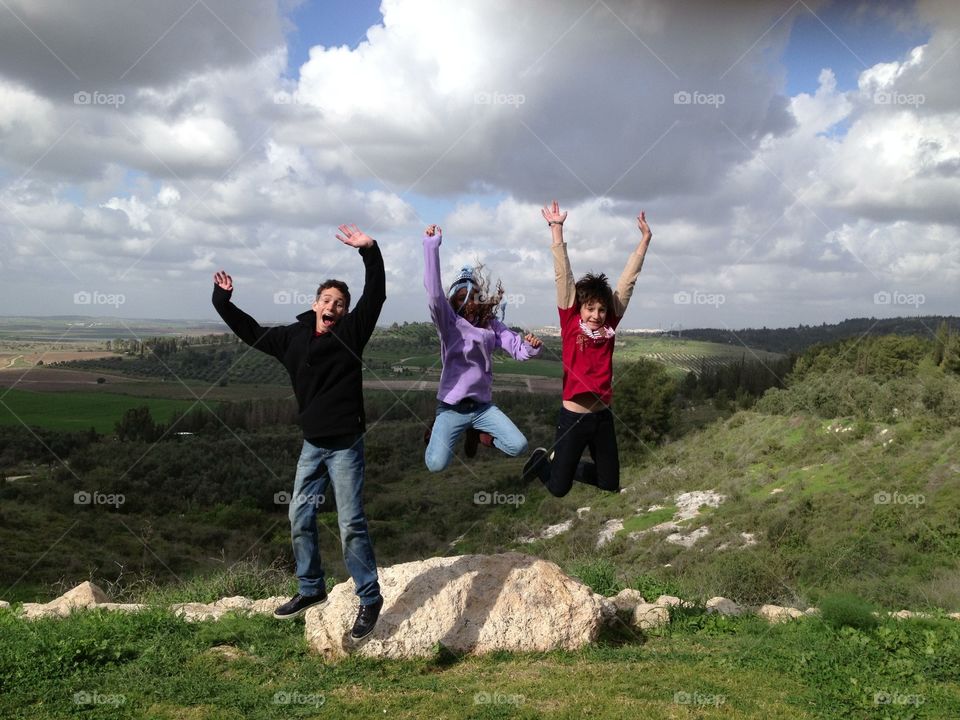 Kids Having Fun Jumping on Top of a Hill