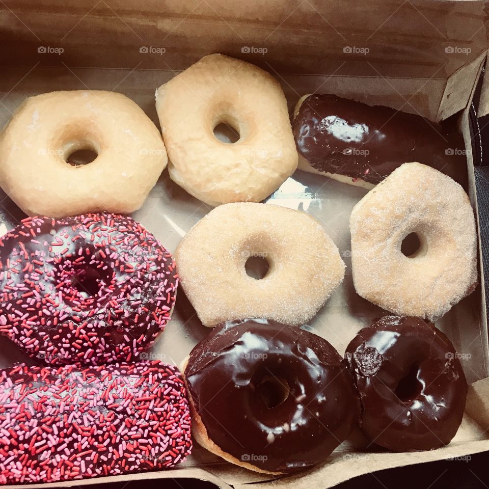 A box of yummy and delicious sugar, pink sprinkled and chocolate donuts in a box. USA, America 