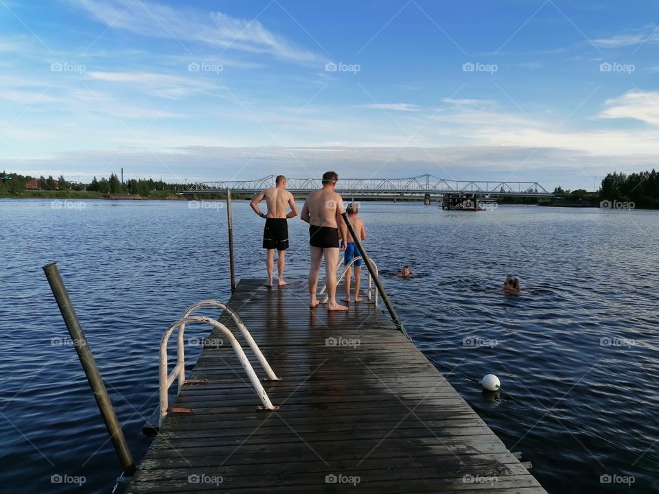 Family swimming in summer in Tornionjoki, Lapland, Finland.