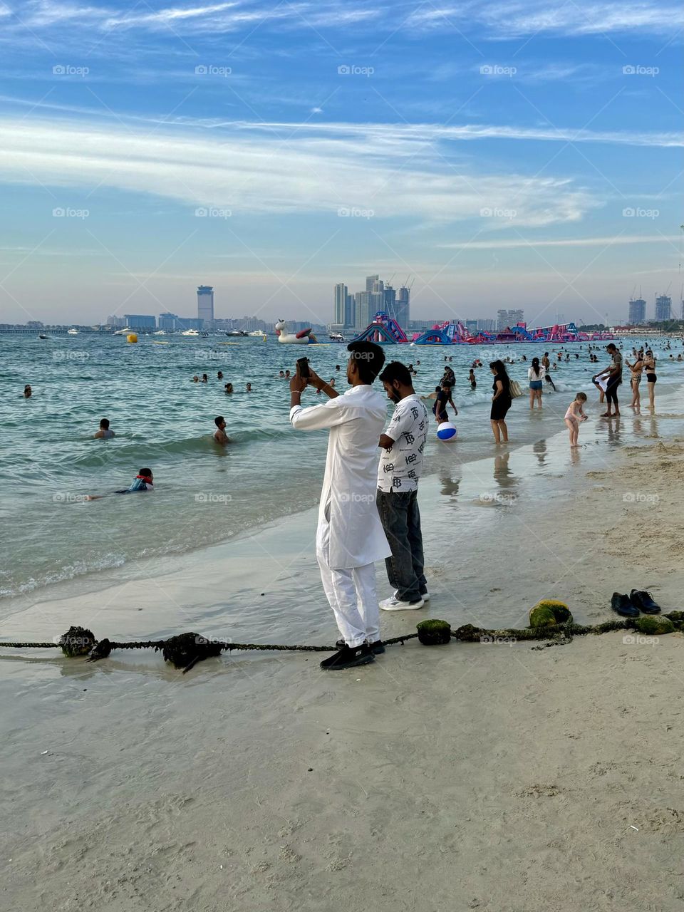 a man in white national clothes films the sea on the beach