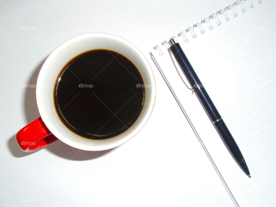 Coffee on the desk with pen and notebook