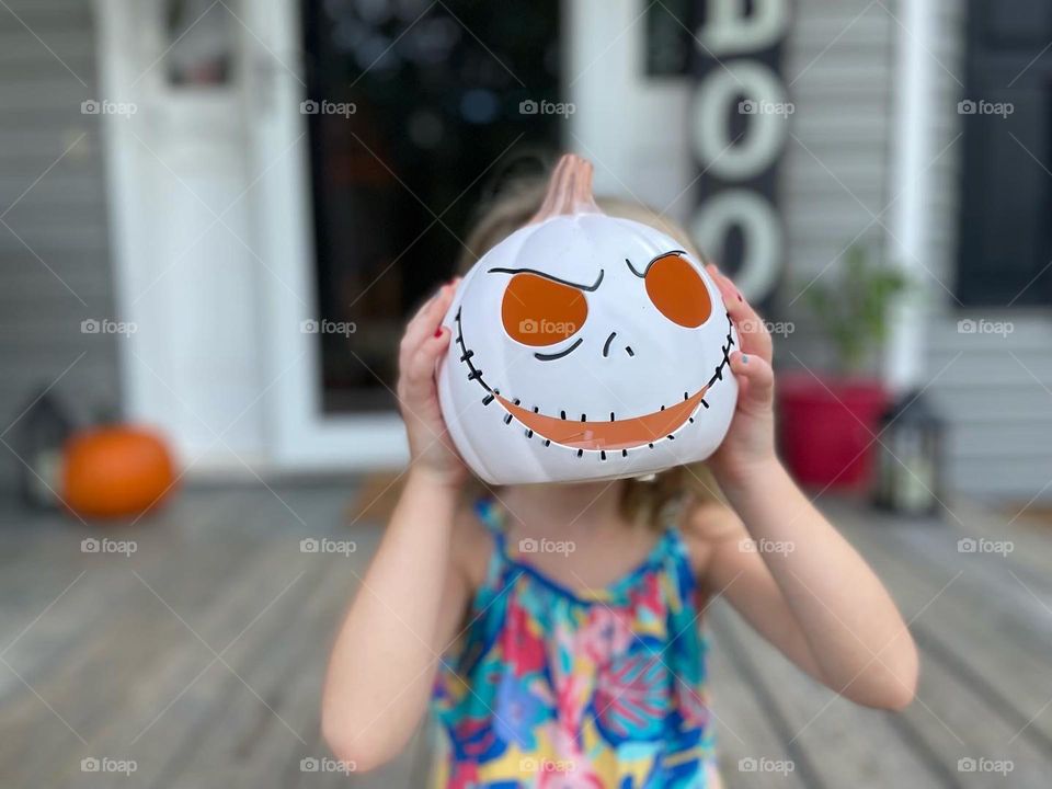 A girl holding a pumpkin in front of her face 