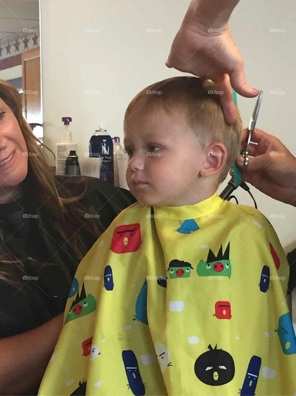 Cute boy getting haircut at salon