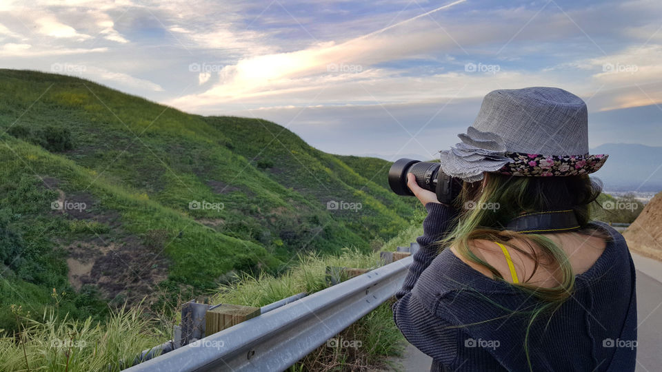 lady holding dslr camera, taking a photo of the hills in spring