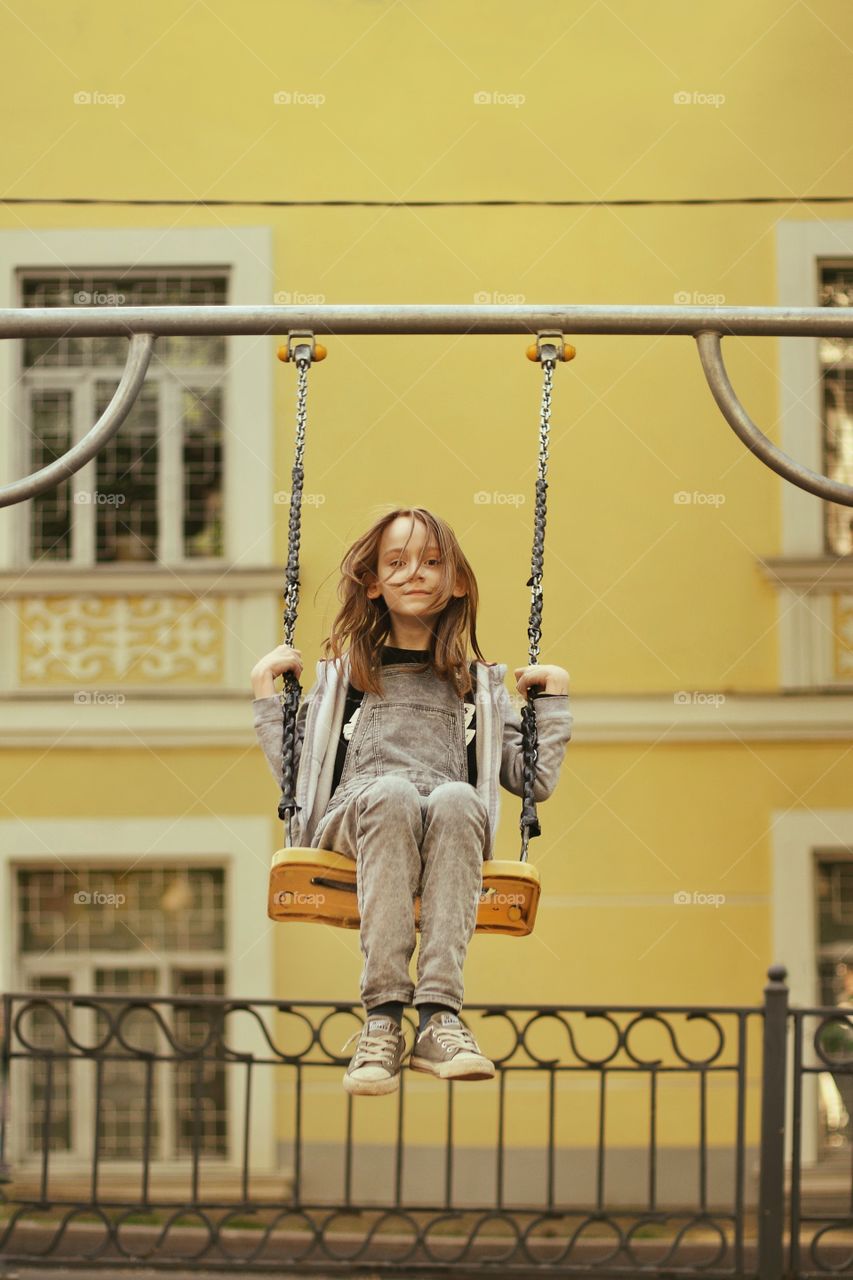 Girl fun swinging on a yellow swing near the yellow house