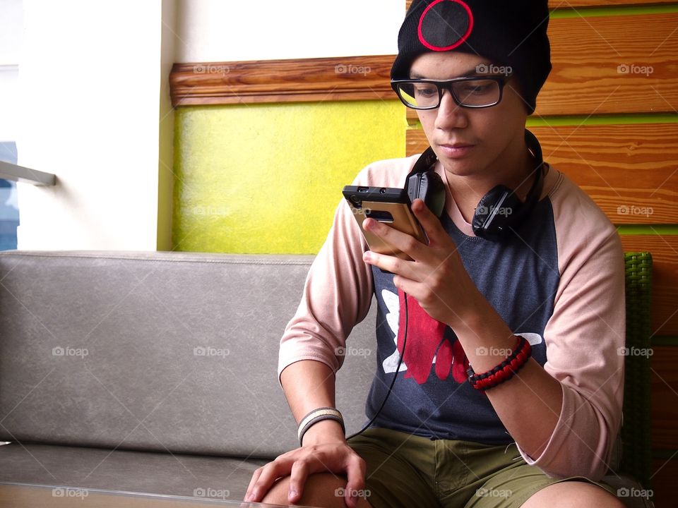 teenage boy wearing bonnet using a smartphone