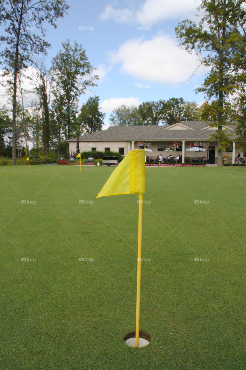 Club house behind a golf putting flag on the green