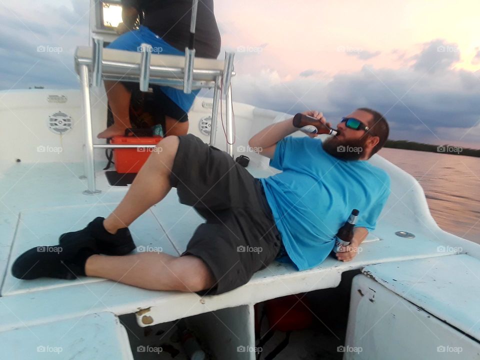 A photo of a man, laying down for a rest and an adult beverage after a cruise on the beautiful waters of Tampa Bay Florida.