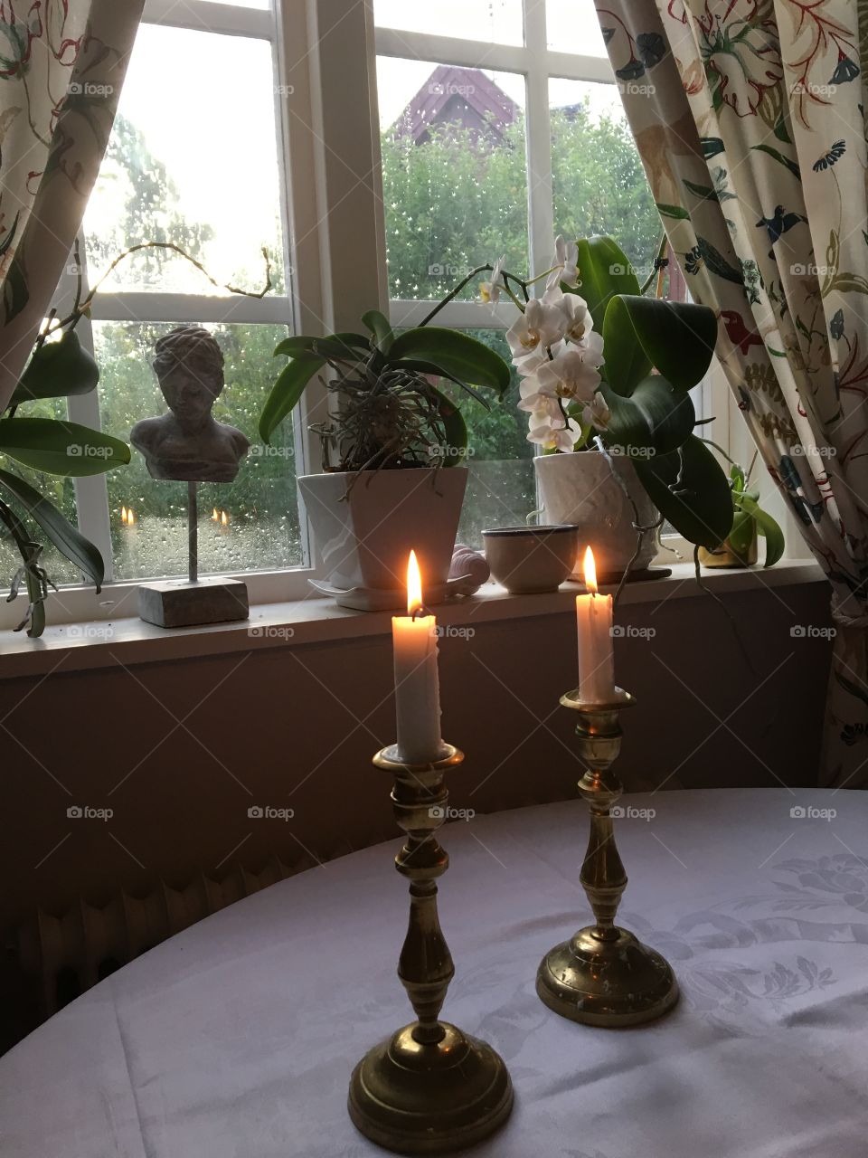Candlelights and flowers  window with raindrops