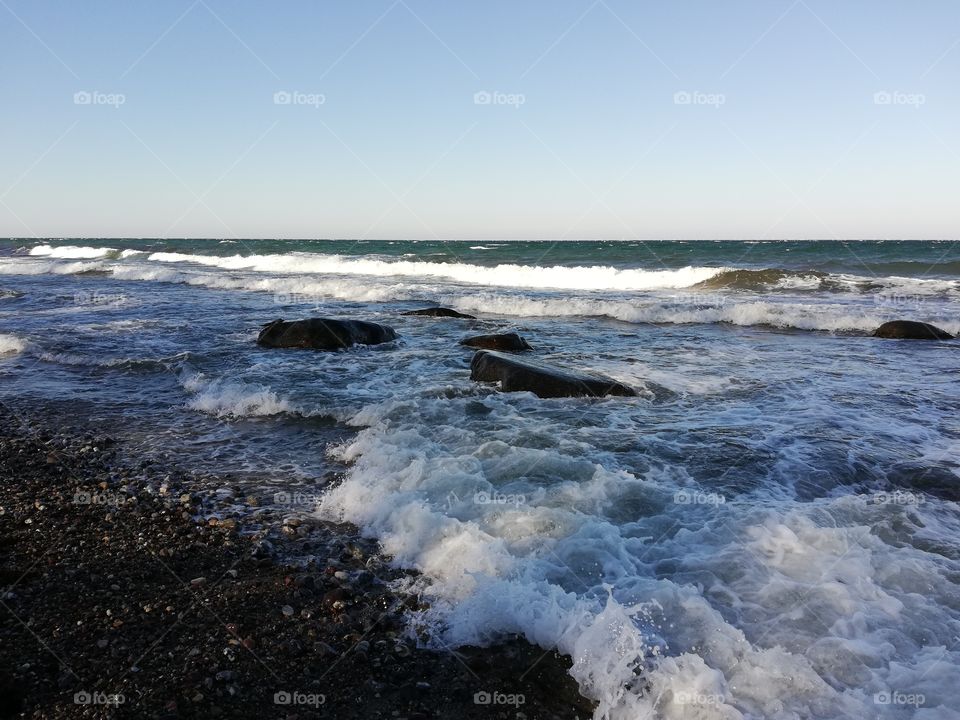 Strand auf Fehmarn mit Steinen, Wellen und dem weiten Horizont.